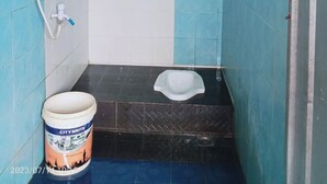 A small bathroom with blue walls, a white toilet, a shower, and a bucket labeled "CITY BRITE". - Ekost Bayeman (Sleman)