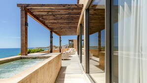 A modern outdoor terrace with a pool, wooden pergola, and glass walls offering a view of the sea. - Stunning Oceanview Condo (San José del Cabo)