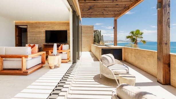 A modern outdoor living area with a sofa set, a TV, and a view of the ocean. - Stunning Oceanview Condo (San José del Cabo)