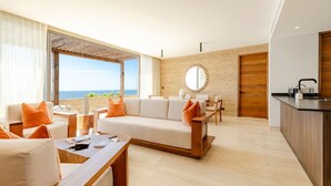 A modern living room with a sofa, coffee table, and dining area. There is a large window with a view of the ocean. - Stunning Oceanview Condo (San José del Cabo)