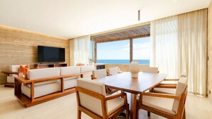 A modern living room with a large wooden dining table, comfortable seating, a flat-screen TV, and a view of the ocean. - Stunning Oceanview Condo (San José del Cabo)