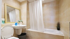 A modern bathroom with a toilet, sink, and bathtub.