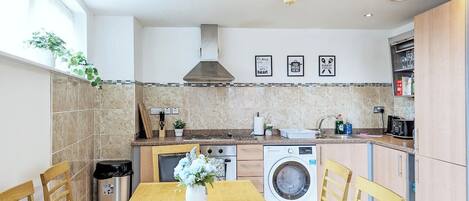 Una cocina moderna con comedor, lavadora y lavaplatos.