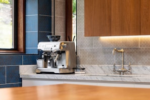 Een keuken met een koffieapparaat, een spoelbak met kraan en een raam.