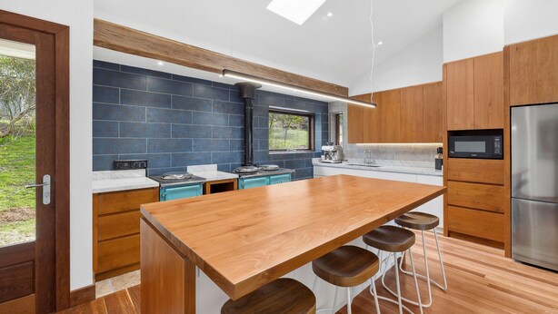 A modern kitchen with a central island, wooden cabinets, and a large window. - Chatby House filtered views of the ocean (Lorne)