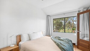 A bedroom with a bed, bedside table, lamp, and a window with curtains. - Chatby House filtered views of the ocean (Lorne)