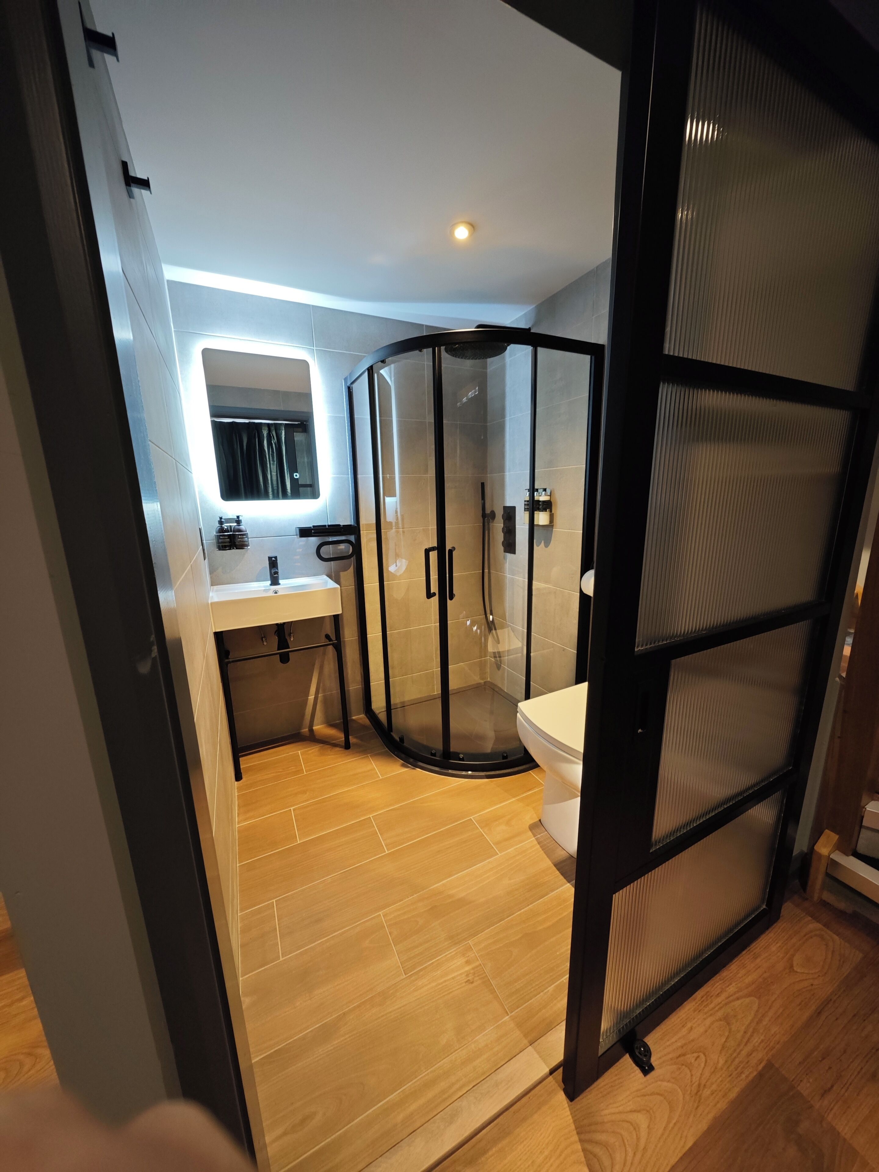 A modern bathroom with a glass-enclosed shower, a sink, and a toilet.