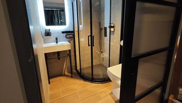 A modern bathroom with a glass-enclosed shower, a sink, and a toilet.