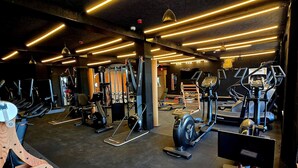 A gym with various exercise equipment, including treadmills, elliptical machines, and weight machines.