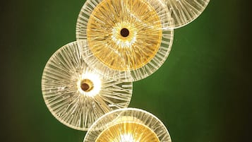 Una serie de luminarias circulares con una bombilla central, dispuestas verticalmente sobre un fondo verde.