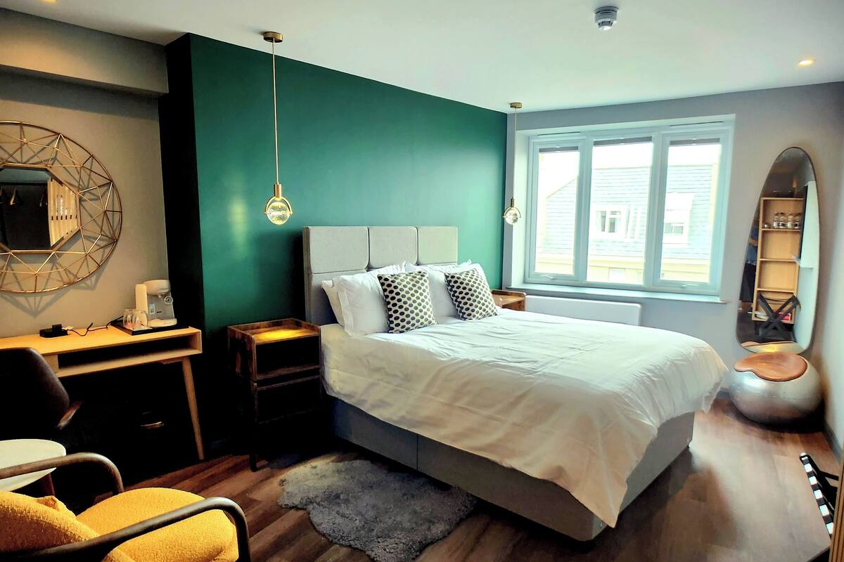 Un dormitorio moderno con una cama grande, un escritorio y una silla.