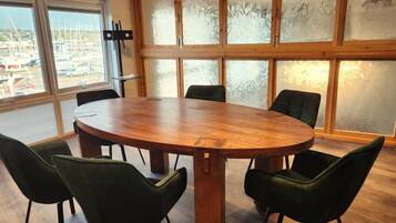 A conference room with a large wooden table and six green chairs.