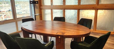 A conference room with a large wooden table and six green chairs.
