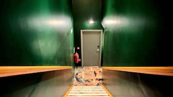 Un pasillo con paredes verdes y una alfombra estampada que lleva a una puerta.