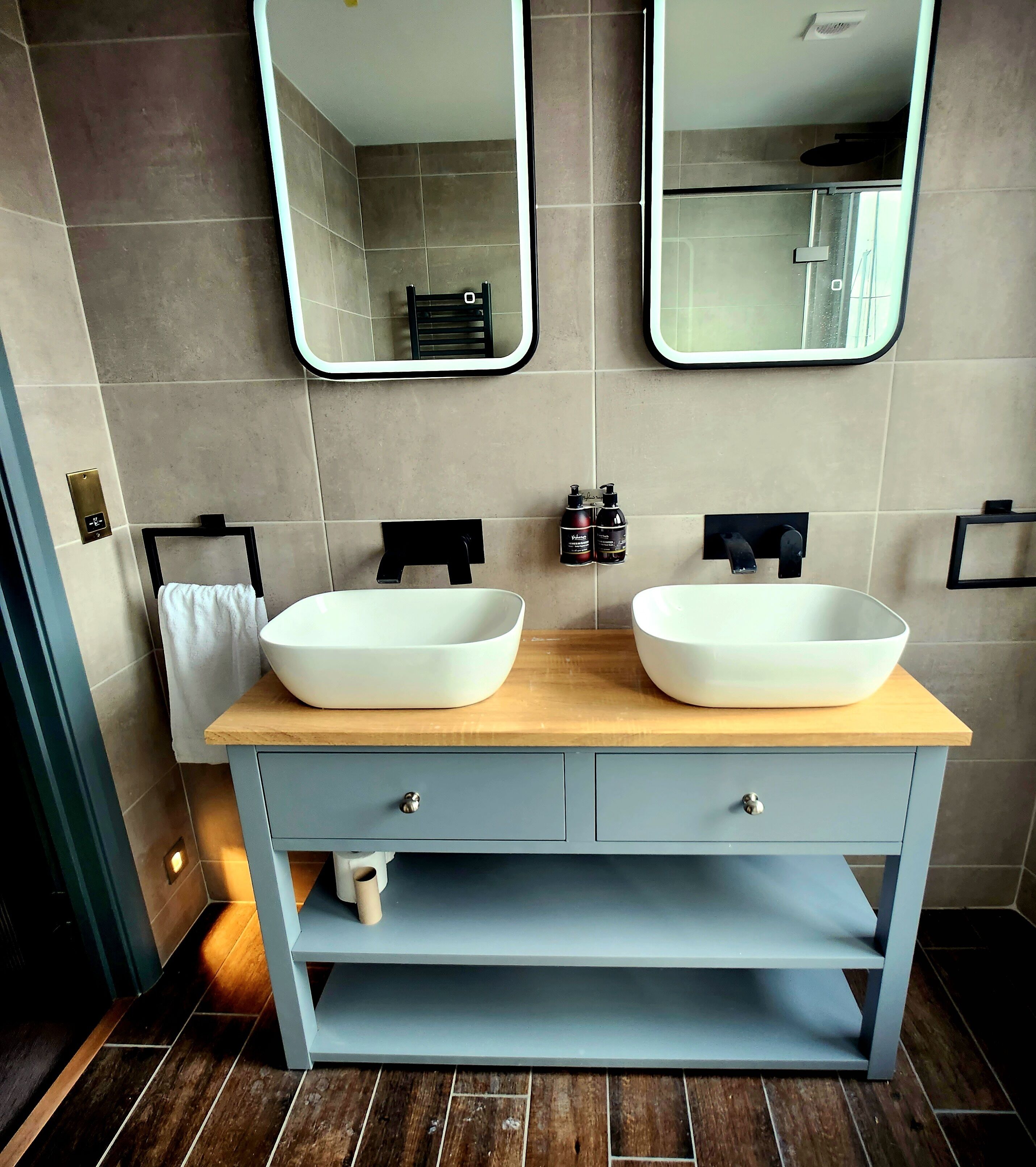 A bathroom with two white sinks, a wooden countertop, and two mirrors.