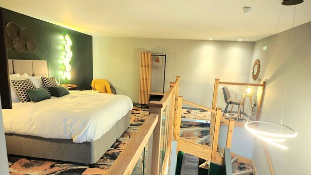 A bedroom with a bed, a wooden bench, a staircase, and a wall-mounted light fixture. - Pinnacle Suites (Cowes)