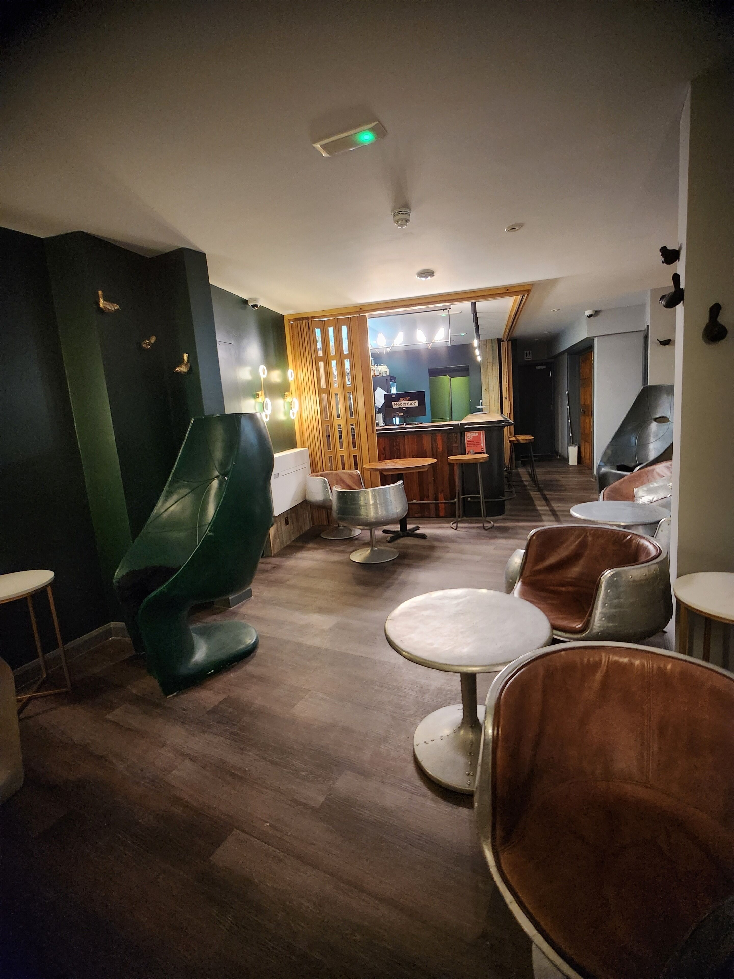 Ein modernes Interieur mit einer Rezeption, grün-braunen Polsterstühlen und Holzboden.