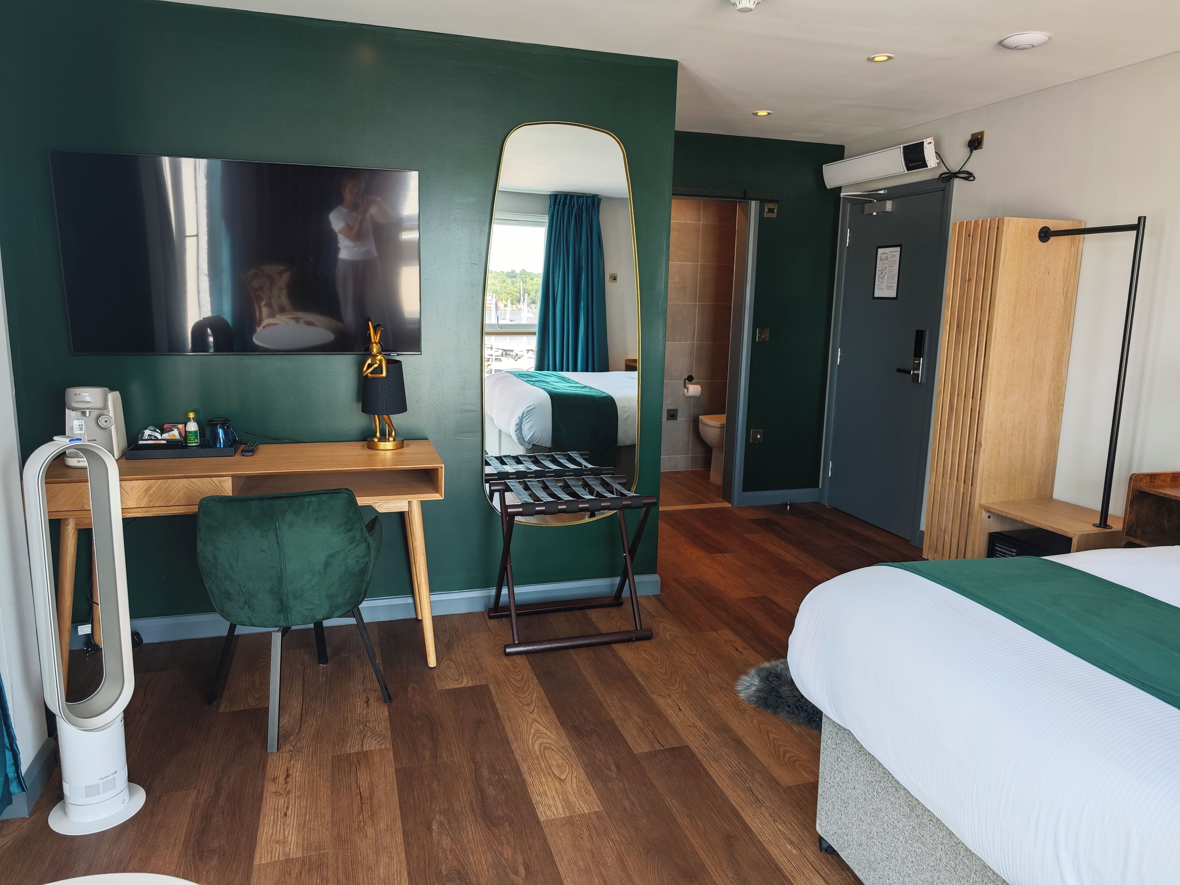 Une chambre d’hôtel avec un lit, un bureau, une chaise et un miroir.