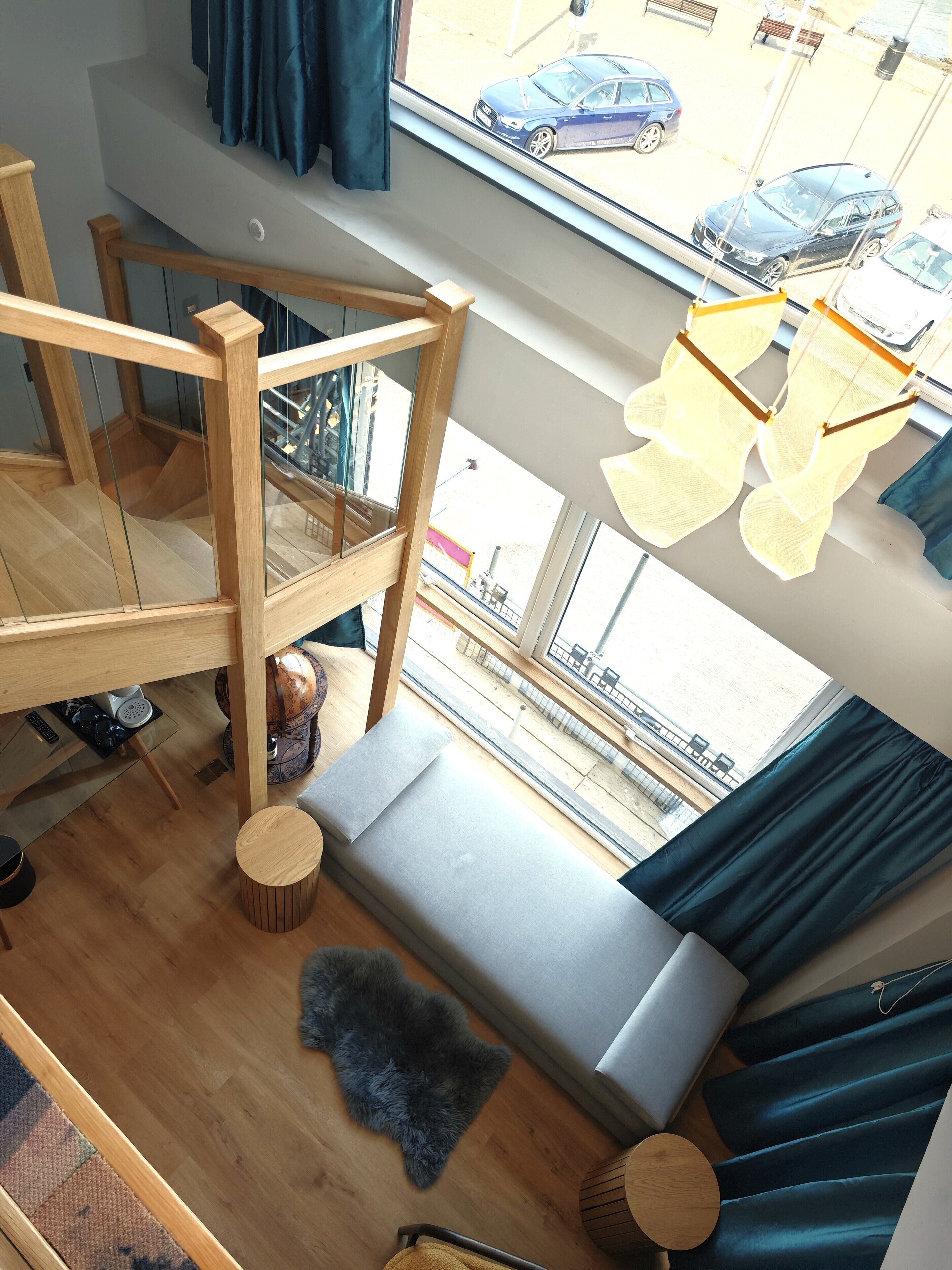 A high-ceiling room with a wooden bunk bed, a cushioned seating area with a view of the street, and a small round table.