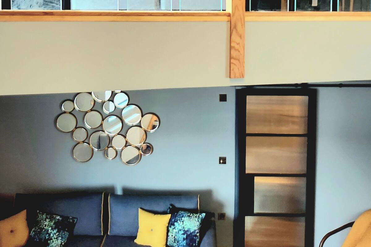 Una habitación moderna con una cama, un sofá y un espejo circular en la pared.