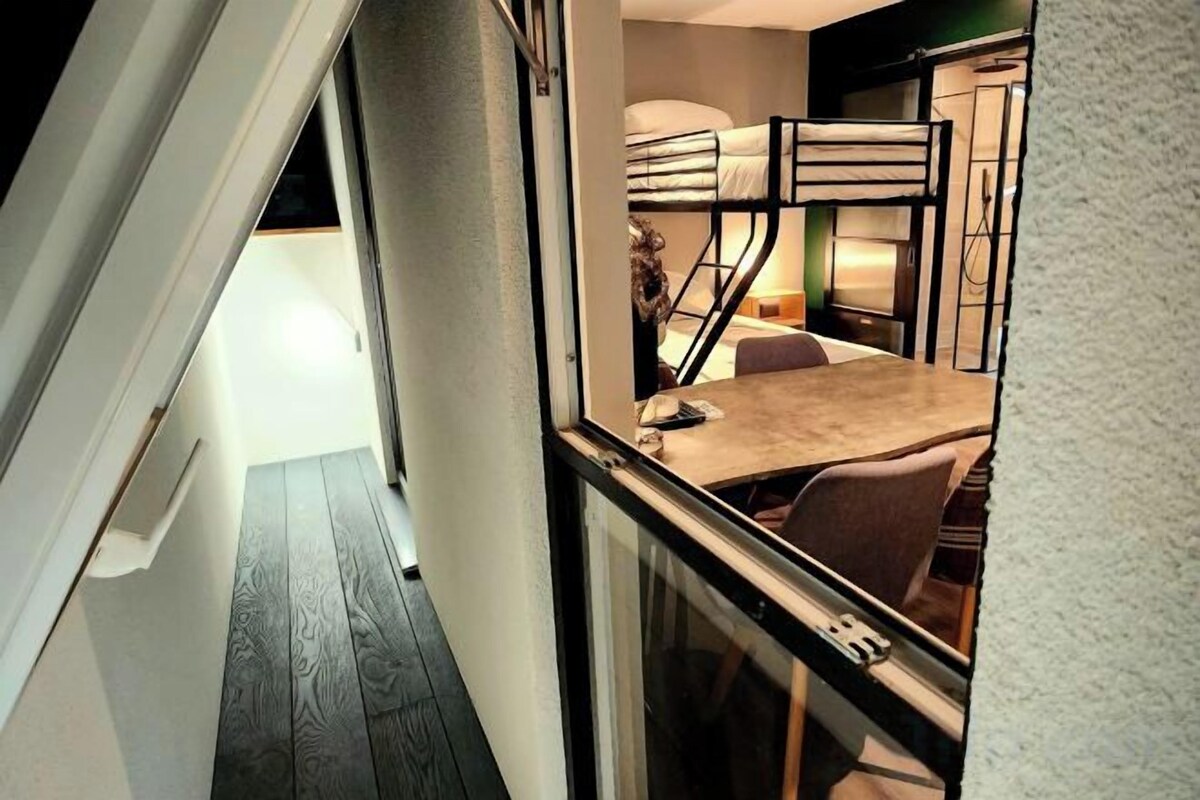 A narrow hallway leading to a room with bunk beds, a table, and chairs.