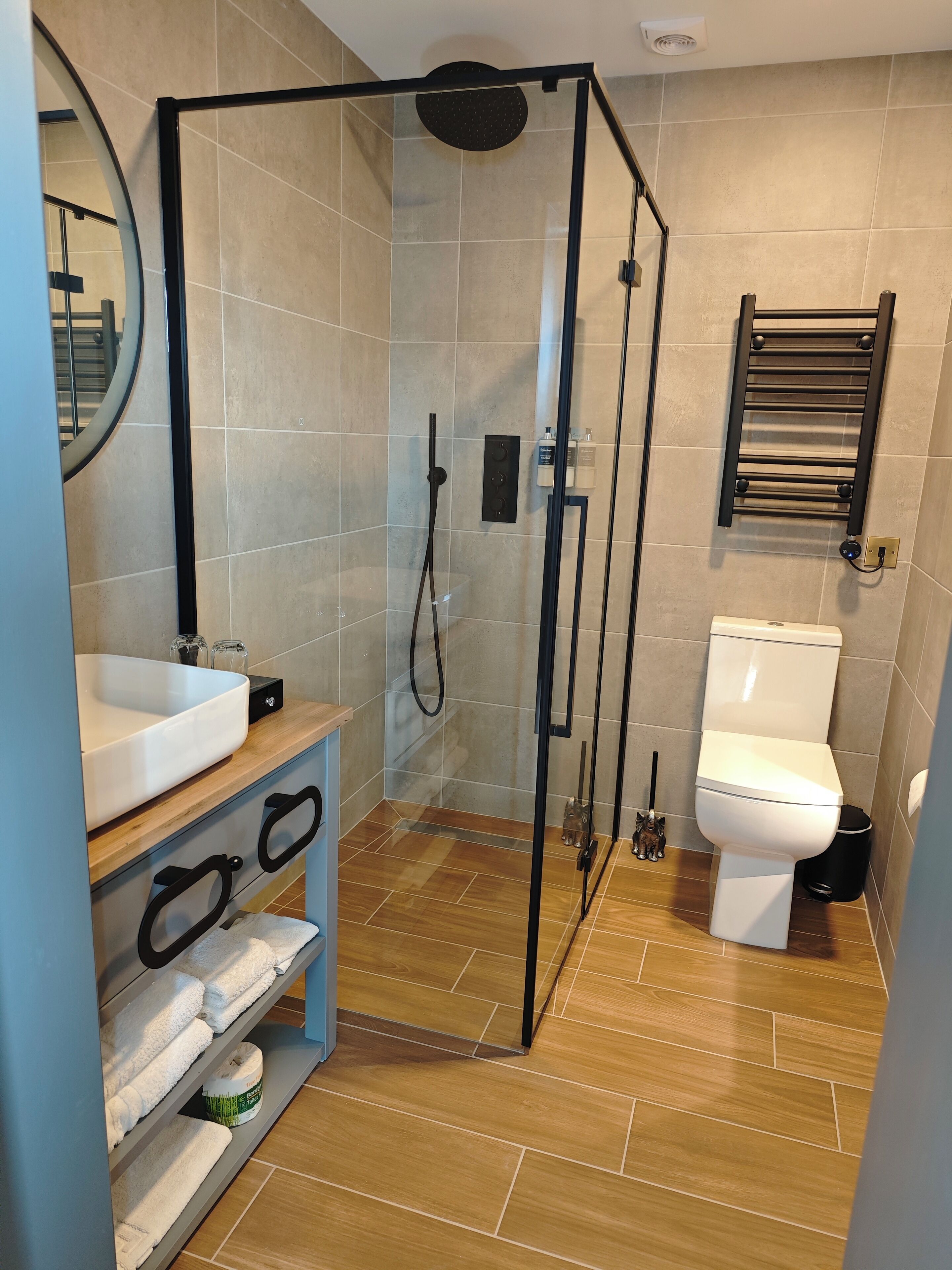 Une salle de bain moderne avec une douche à parois de verre, un lavabo blanc, des toilettes et un porte-serviettes.
