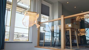 A modern interior with large windows, a wooden staircase, and a unique hanging light fixture. - Pinnacle Suites (Cowes)