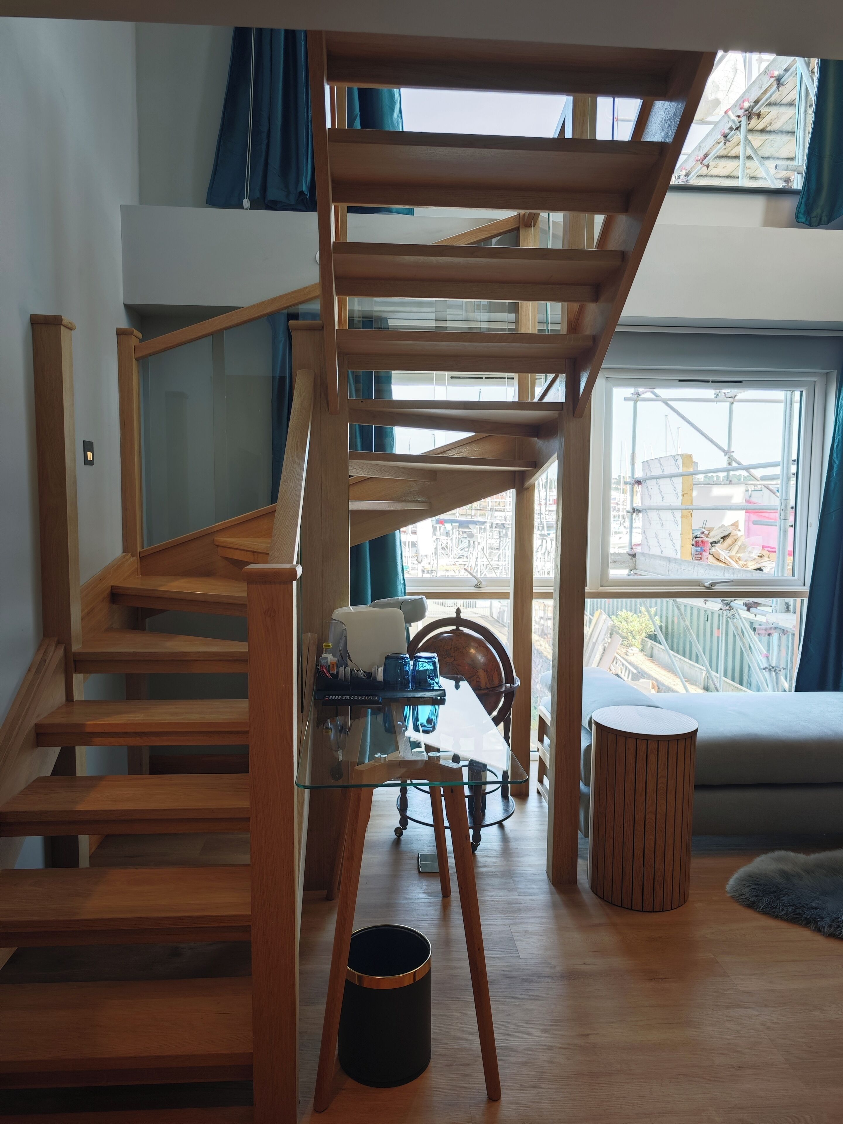 Una escalera de madera con barandilla de vidrio que lleva a un balcón.