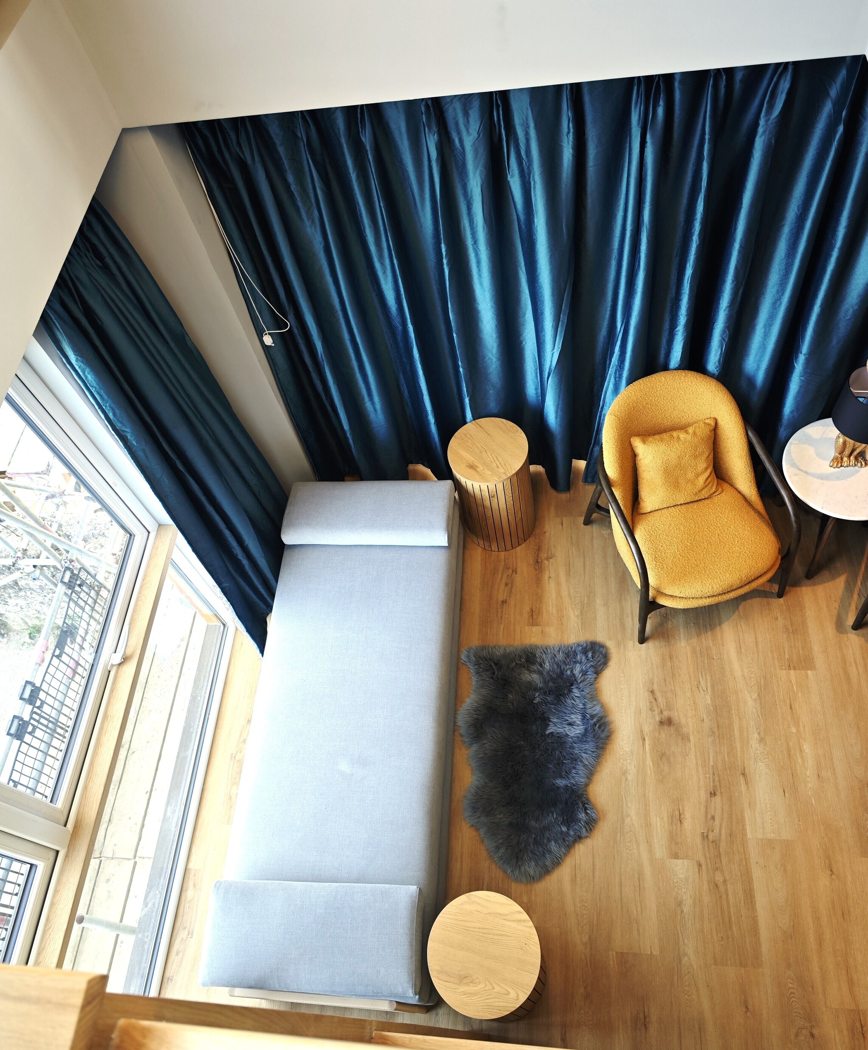 Une pièce comprenant un canapé, un fauteuil, une petite table, un tapis et une fenêtre avec des rideaux.