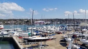 A marina with numerous boats docked, a clear sky, and a town in the background. - Pinnacle Suites (Cowes)