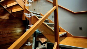 A modern staircase with wooden railings and glass panels, leading to a high ceiling with skylights. - Pinnacle Suites (Cowes)