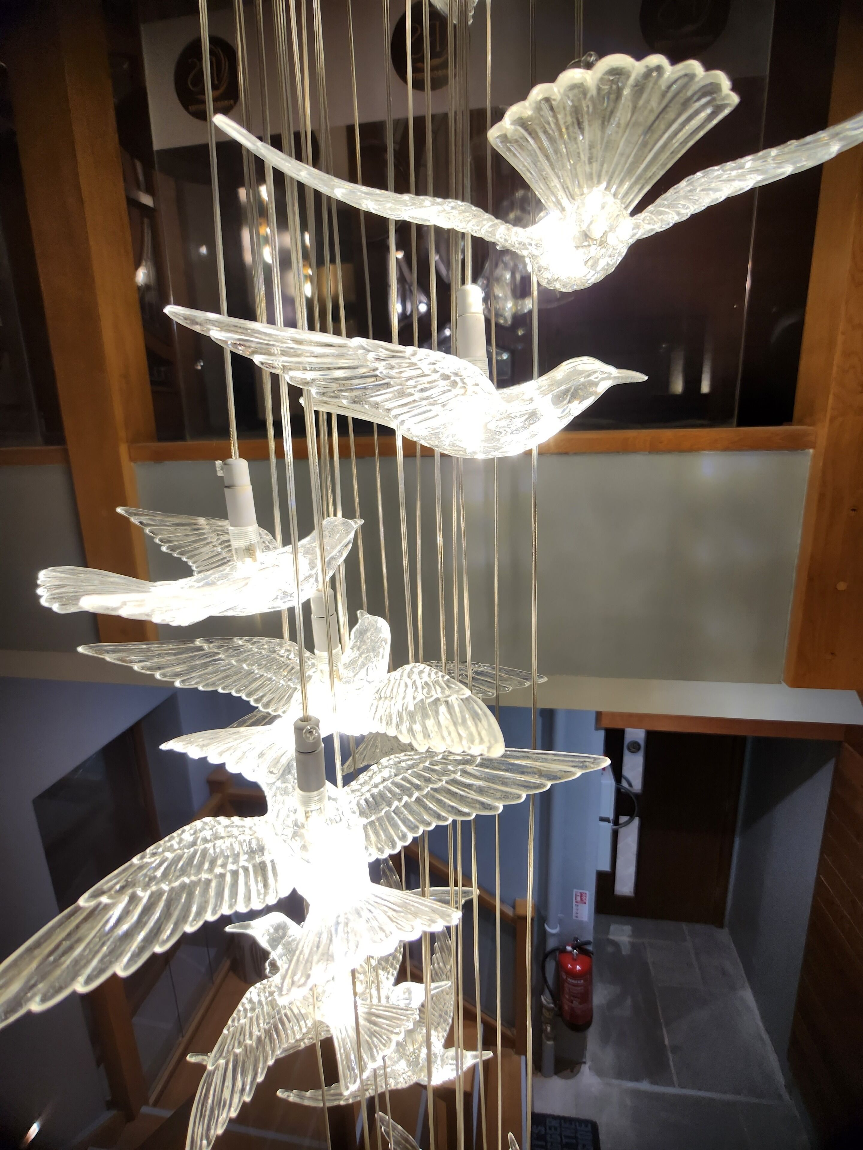 A chandelier with multiple glass bird-shaped elements suspended by thin wires.