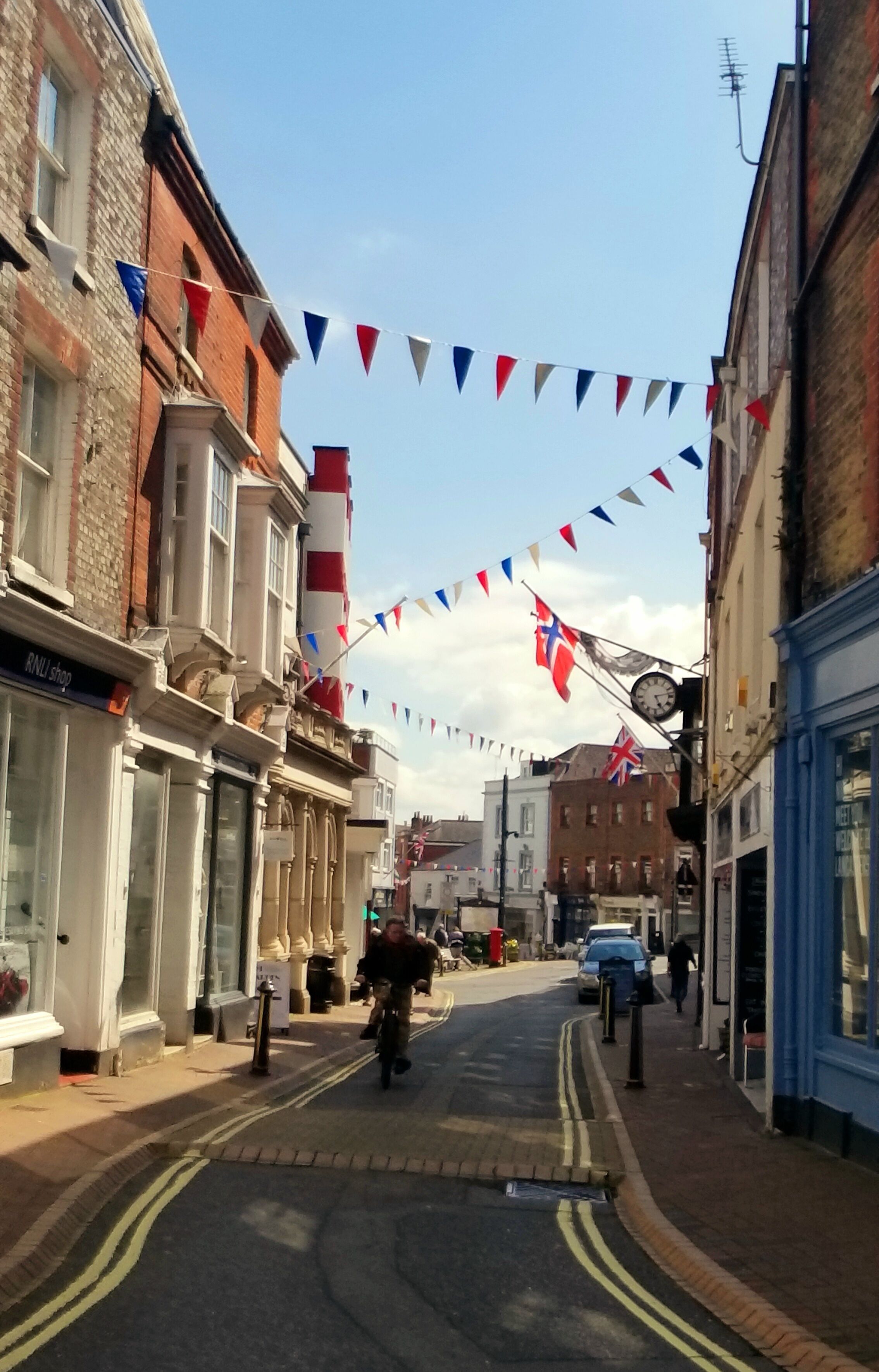A street with buildings, a clock, and flags.