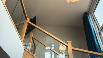 Een houten trap met glazen balustrades en een moderne lamp.