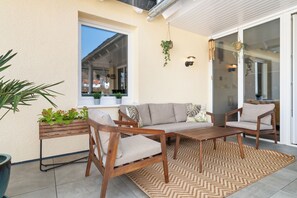 Un patio con sofá, sillas, una mesa y una planta colgante.