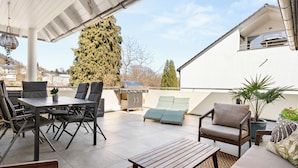Un patio esterno coperto con tavolo, sedie, una poltrona prendisole e un barbecue.