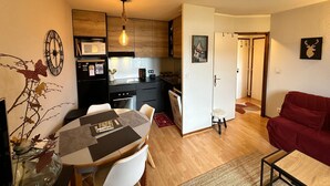 A compact living space with a dining area, kitchenette, and a red sofa. - Lovely 2-room apartment, south balcony, mountain view, WIFI, 4 pax (Villard-de-Lans)