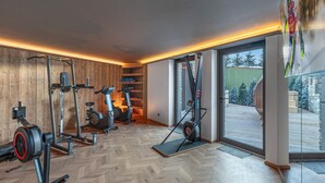 Un gimnasio con equipo de ejercicio, paredes de madera y un ventanal grande.