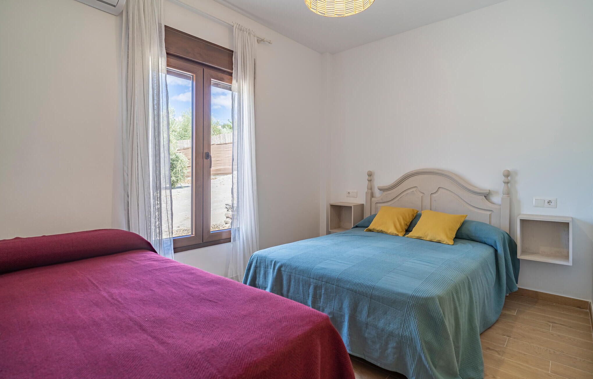 A bedroom with two beds, a window with curtains, and a ceiling light.