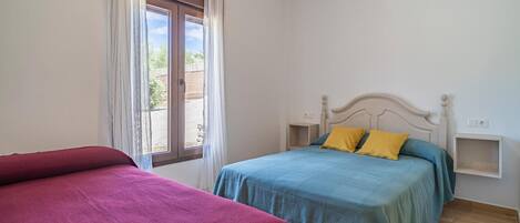 A bedroom with two beds, a window with curtains, and a ceiling light.