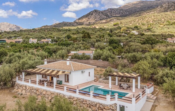 Relax by the outdoor pool surrounded by lush greenery and a mountainous backdrop.
