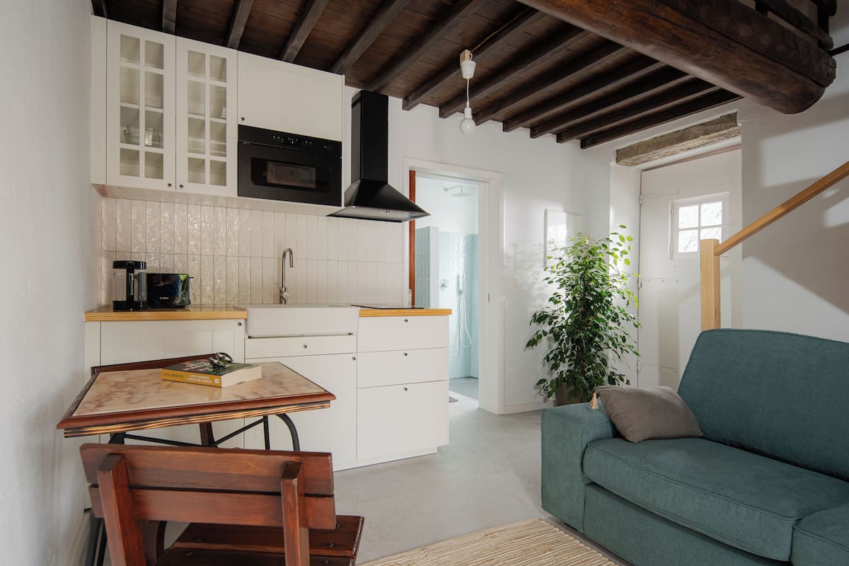 A compact kitchen with white cabinetry, a wooden table, and a green sofa.