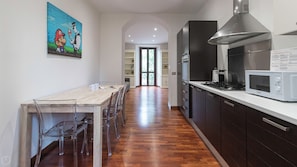 A modern kitchen with a wooden dining table, chairs, a microwave, and a range hood. - Italianway Easy - Buonarroti 5 (Milan)