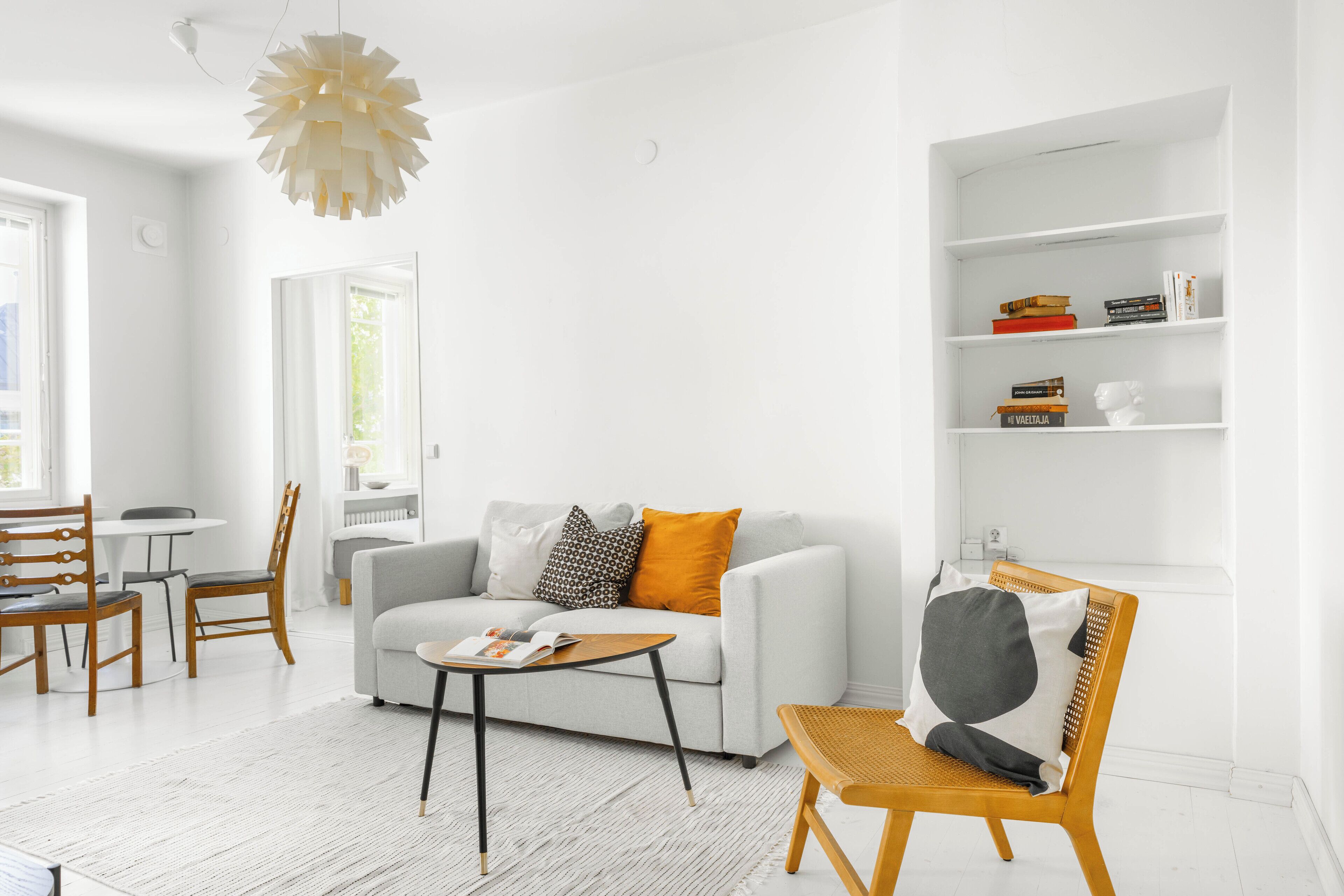 A modern living room with a white sofa, a coffee table, and a bookshelf.