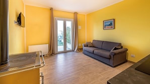 Een woonkamer met een bank, een open haard en een schuifpui naar een balkon.