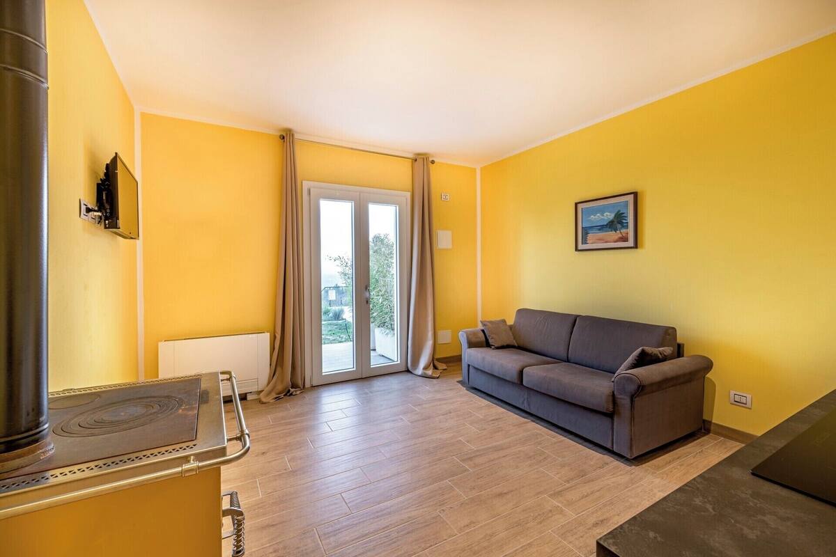 Ein Wohnzimmer mit einer Couch, einem Kamin und einer Schiebetür, die auf einen Balkon führt.