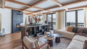 A spacious living area with a fireplace, a large TV, and a balcony with a view of the mountains. - New ski-in/ski-out duplex in Courchevel with parking (Courchevel 1850)