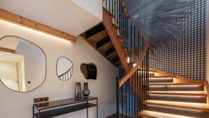 A modern staircase with wooden steps and metal railings, a console table with decorative vases, and a large mirror on the wall. - New ski-in, ski-out duplex with SPA in Courchevel 1850 (Courchevel 1850)