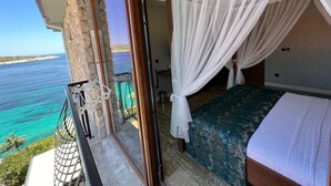 Une chambre avec balcon, un lit et vue sur la mer.