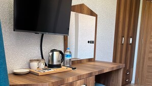 Une petite cuisine équipée d’un téléviseur à écran plat, d’une machine à café, d’une bouteille d’eau et d’un mini-réfrigérateur.